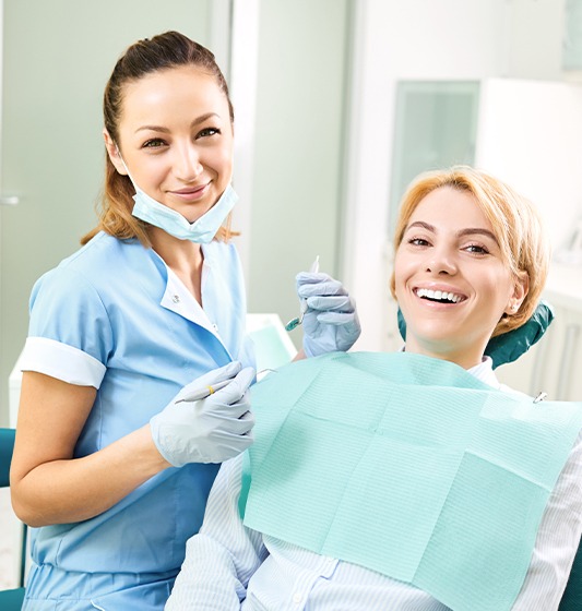 Dental team member helping smiling patient during dental emergency