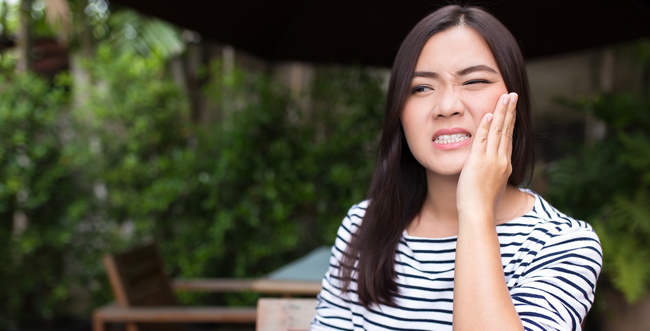 Woman in need of emergency dentistry holding cheek in pain