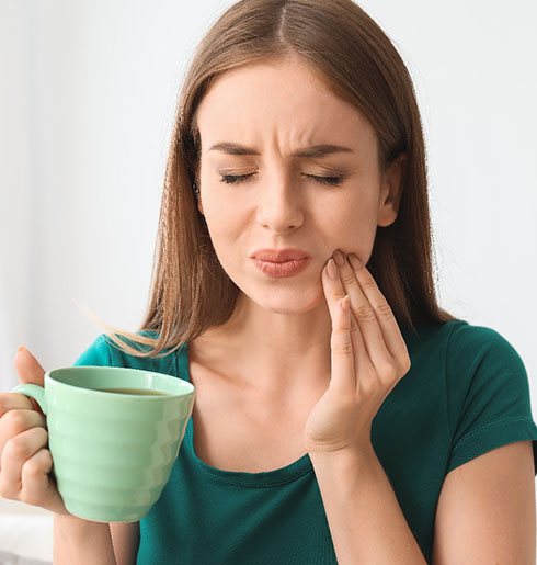 Woman with toothache while holding green mug