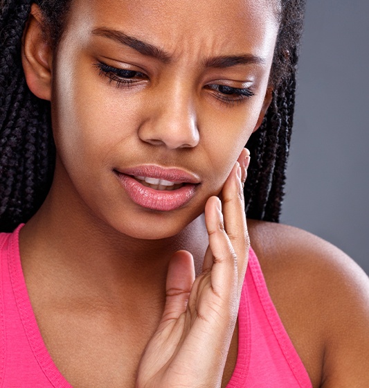 Woman in need of emergency dentistry holding her jaw