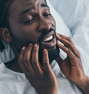 Man with jaw pain holding his face