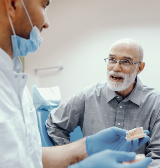 Dentist and patient looking at dental implant model