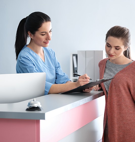 Dental team member and patient reviewing dental insurance forms