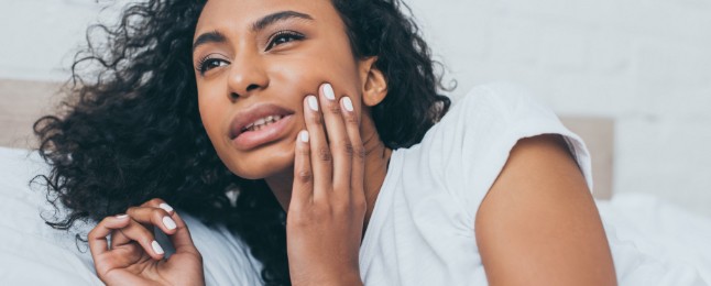 Woman in need of emergency dentistry holding jaw