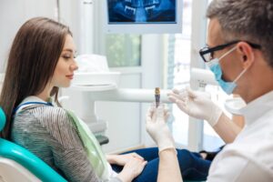 Dentist showing patient dental implant. 