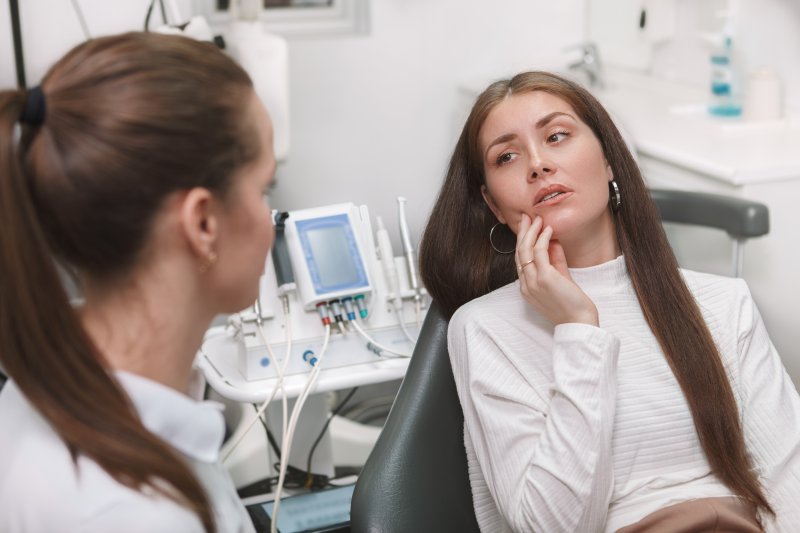 Patient needing a root canal holding cheek in pain at dentist