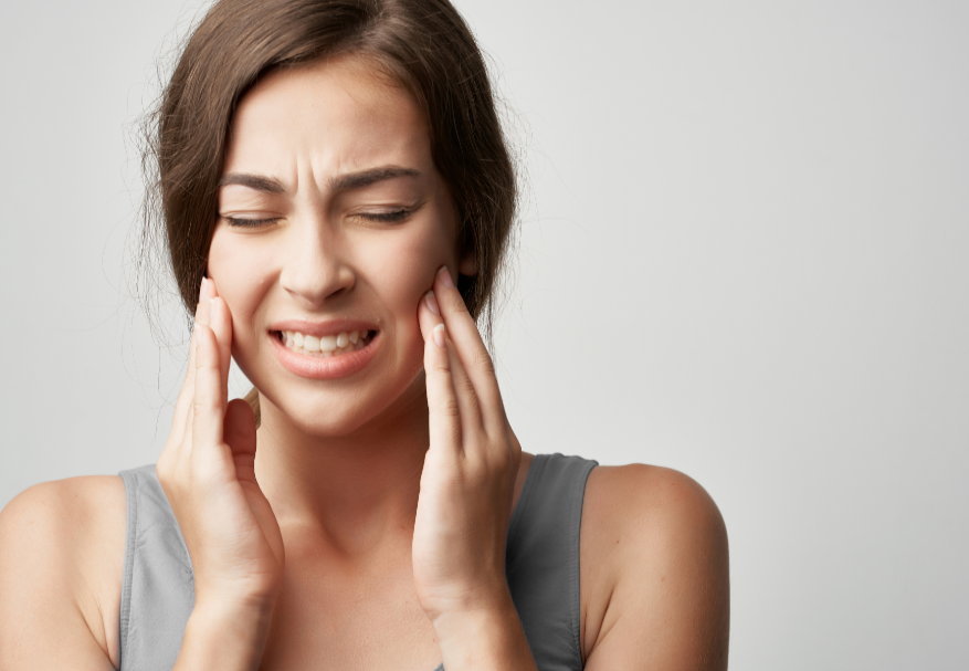 Woman holding jaw and wincing